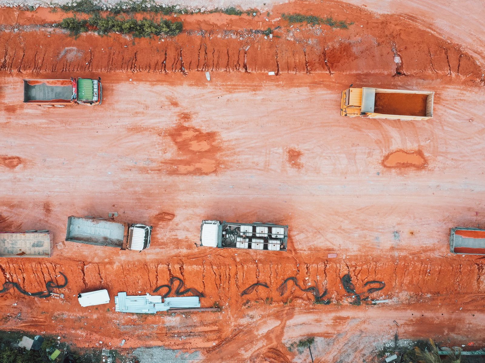 Aerial view of red earthworks with parked trucks